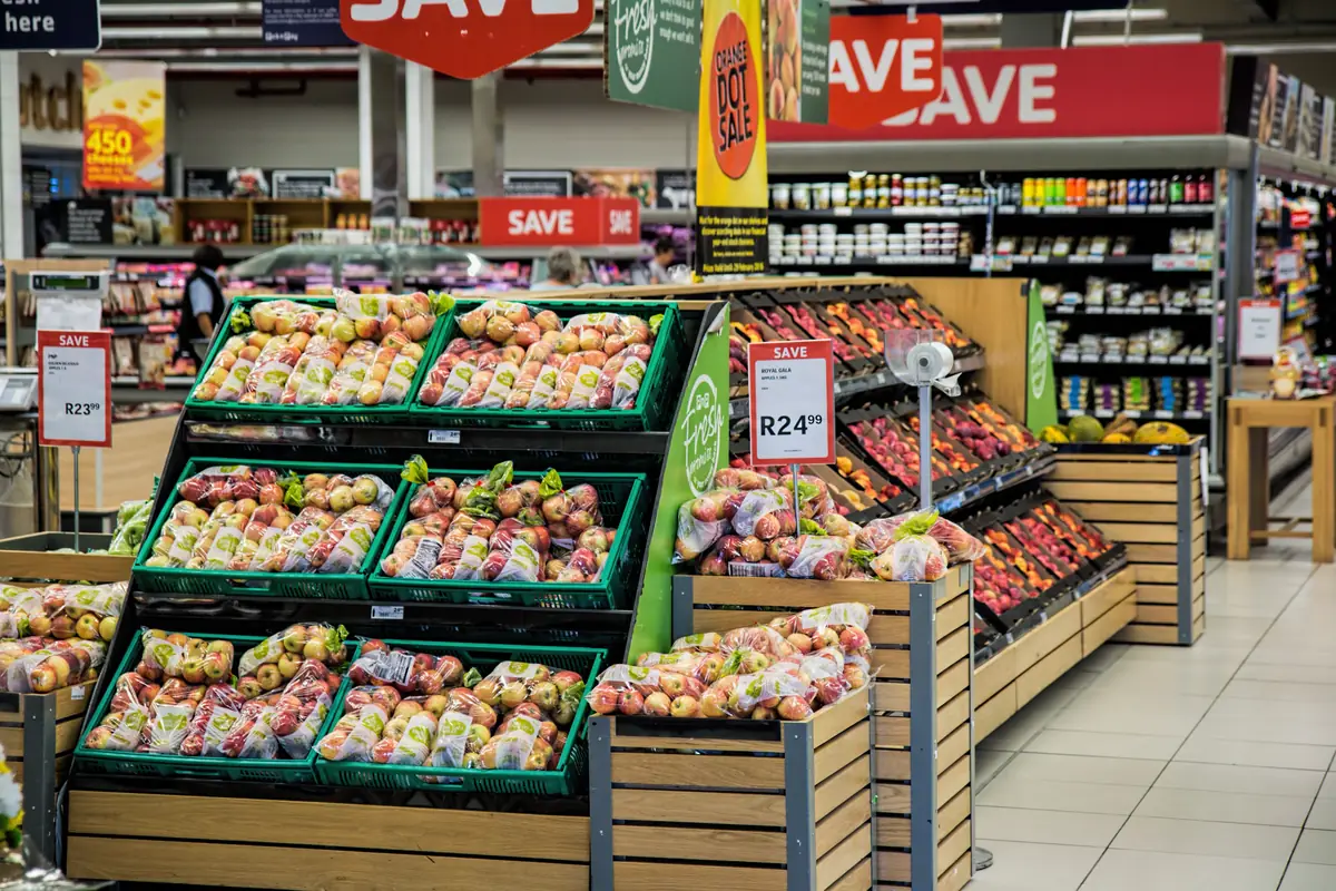 A supermarket produce section with crates of fresh vegetables and fruit